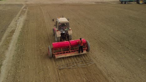 Tractor,-agricultural-machinery-and-workers-sow-a-field---aerial-tracking-shot-1