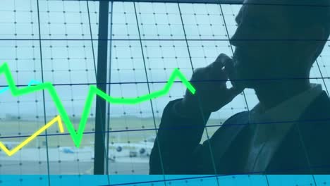 Animation-of-graphs-moving-against-caucasian-businessman-talking-on-smartphone-at-an-airport