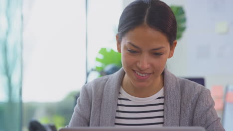 Close-Up-Of-Businesswoman-In-Office-At-Desk-Working-On-Laptop