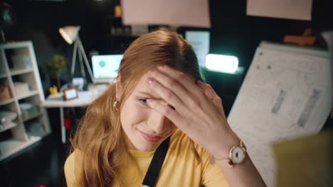 stressed business woman touching forehead in front of glass wall in office.