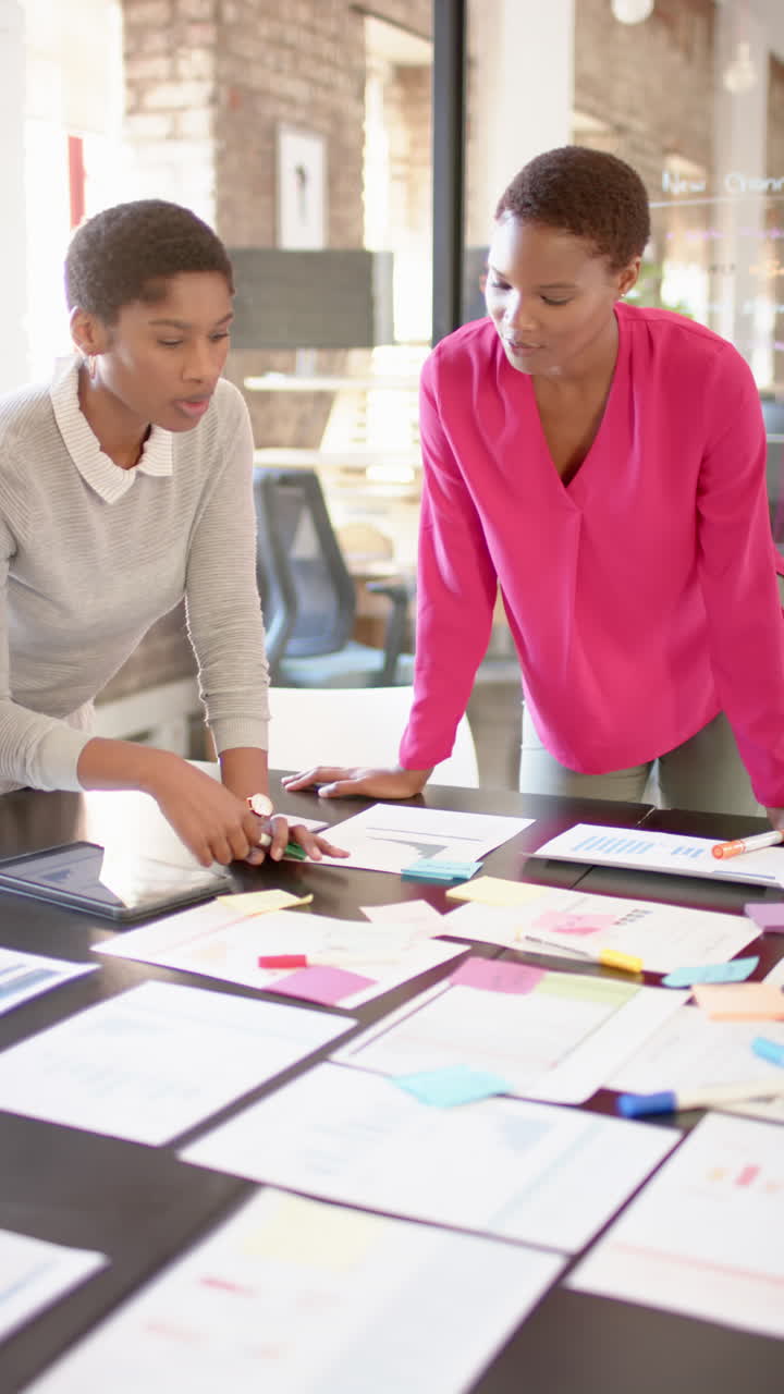 Vertical video of african american colleagues with documents on table discussing work, slow motion