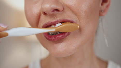 mujer cepillándose los dientes con aparatos dentales