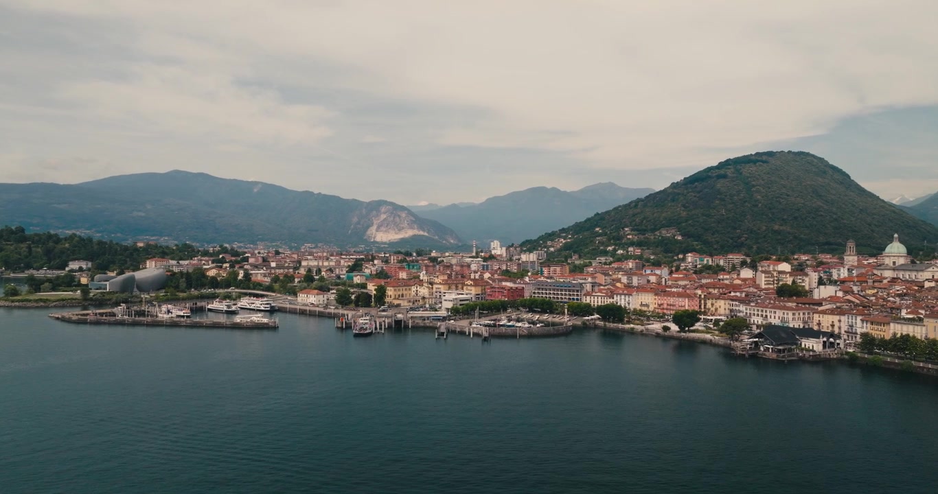 Vista panoramica di Verbania sulle rive del Lago Maggiore, con affascinante architettura lacustre e spettacolari montagne alpine sotto un cielo estivo limpido e azzurro.