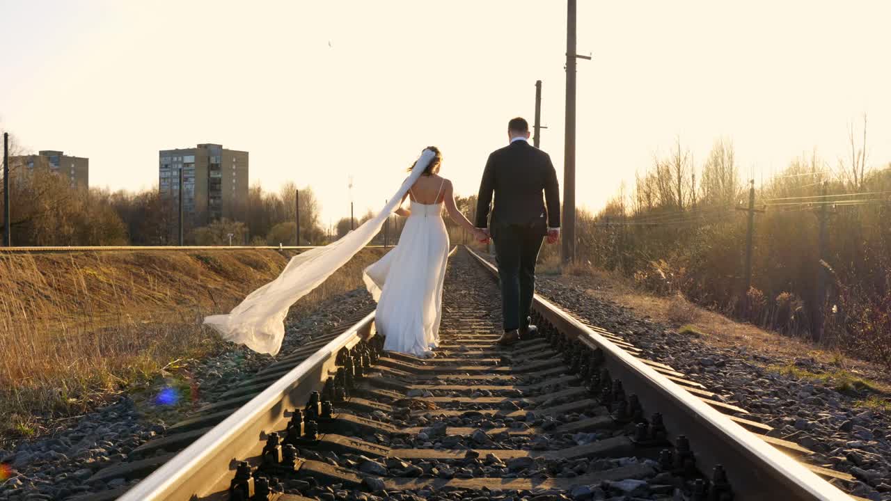 Husband and wife on life journey - walking on train tracks during sunset, back view