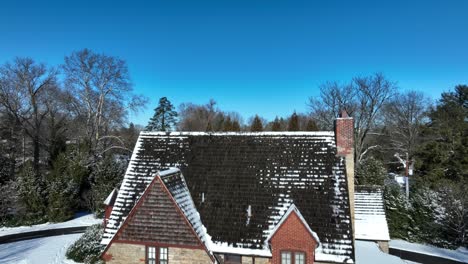 rising aerial shot of an old stone house covered in snow