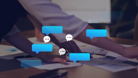 Animation of message icons against mid section of colleagues discussing over documents at office