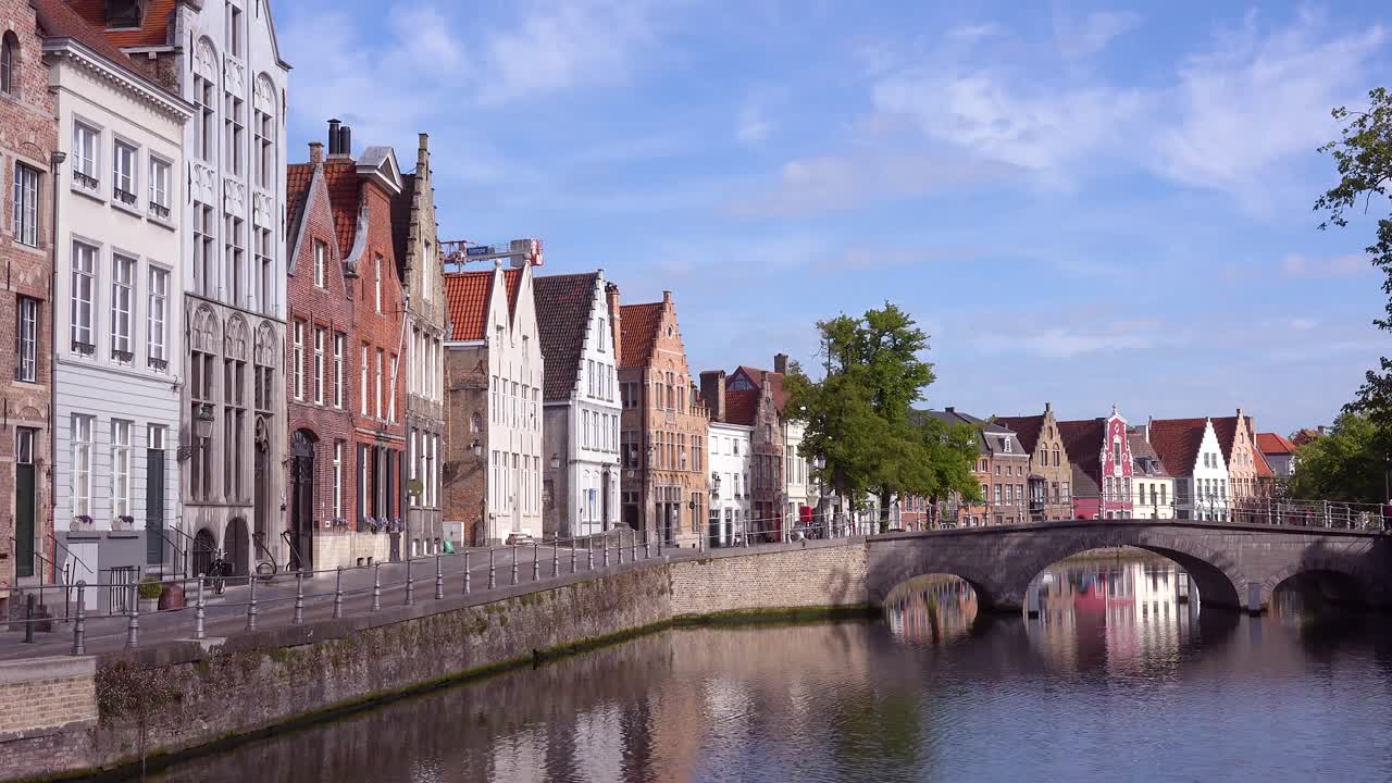 Smukt etableringsskud af en kanal i Brugge, Belgien, med lejligheder og broer.