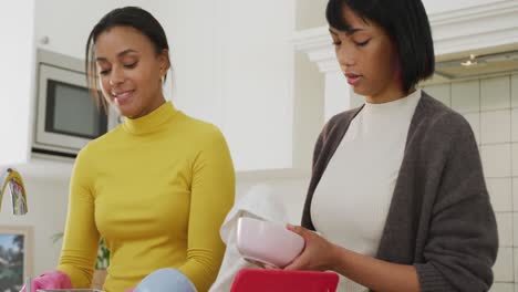 hermanas bi-raciales felices limpiando en la cocina, en cámara lenta.