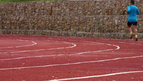 Athlete-runs-on-red-race-track-with-white-lines,-training-for-marathon-long-distance-running