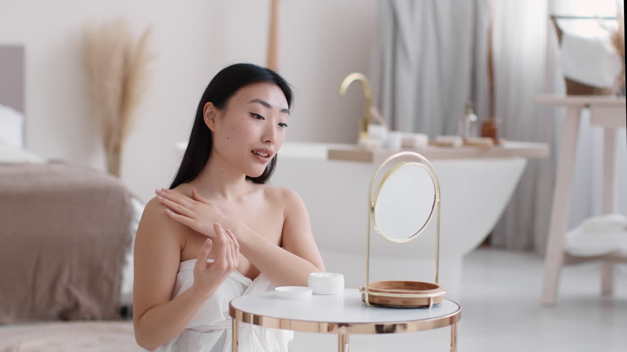 Woman applying skincare in her bedroom