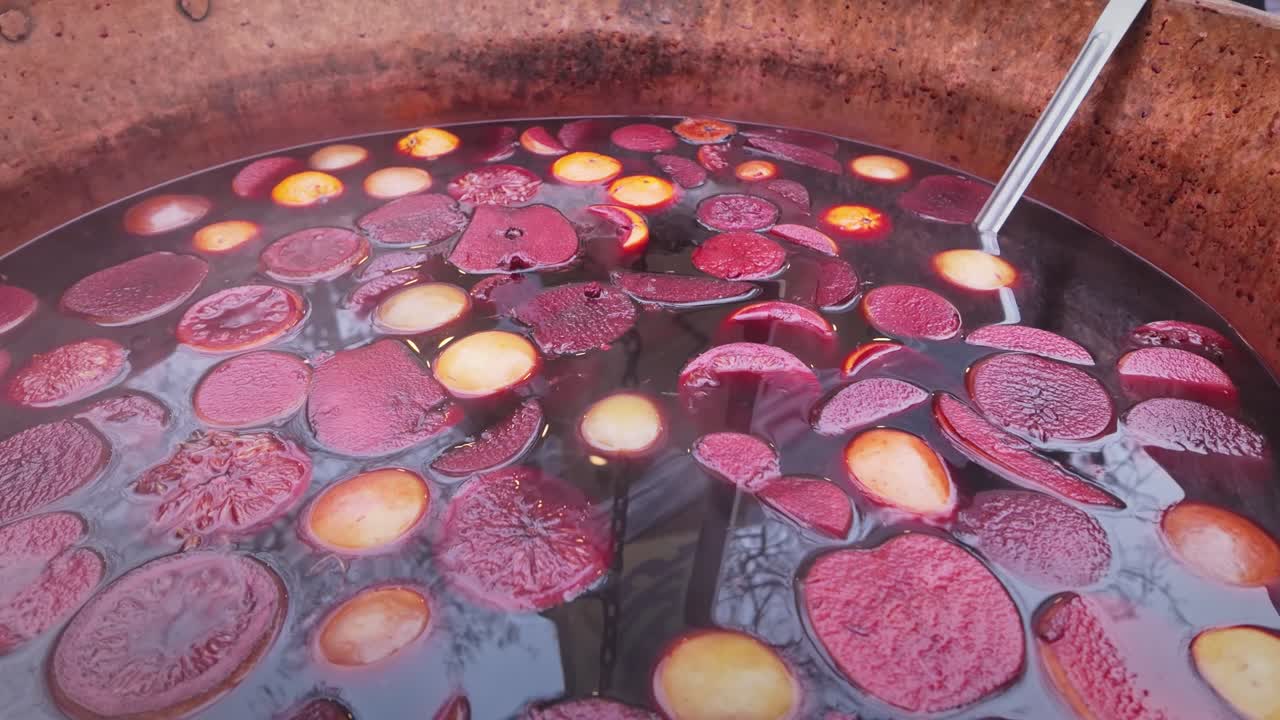 Large pan of hot spiced alcohol mulled fruity wine CLOSE-UP