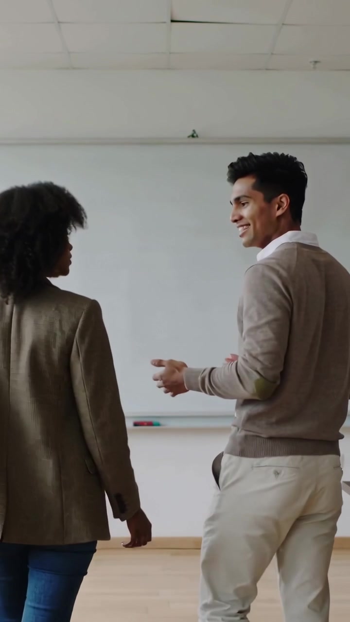 Vertical video: Walking to whiteboard as man talking, peers in blazer sweater gesturing at markers