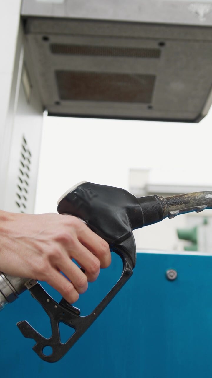 Hand presses fuel gun at gas station