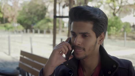 Handsome-Indian-man-talking-by-cell-phone-on-street