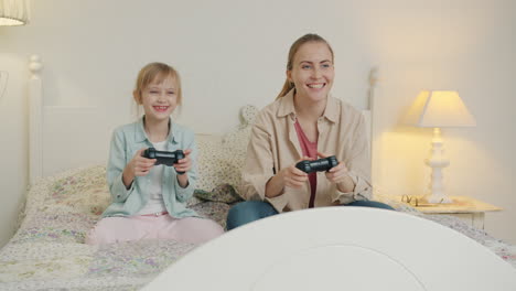 mother and daughter playing video games in bedroom