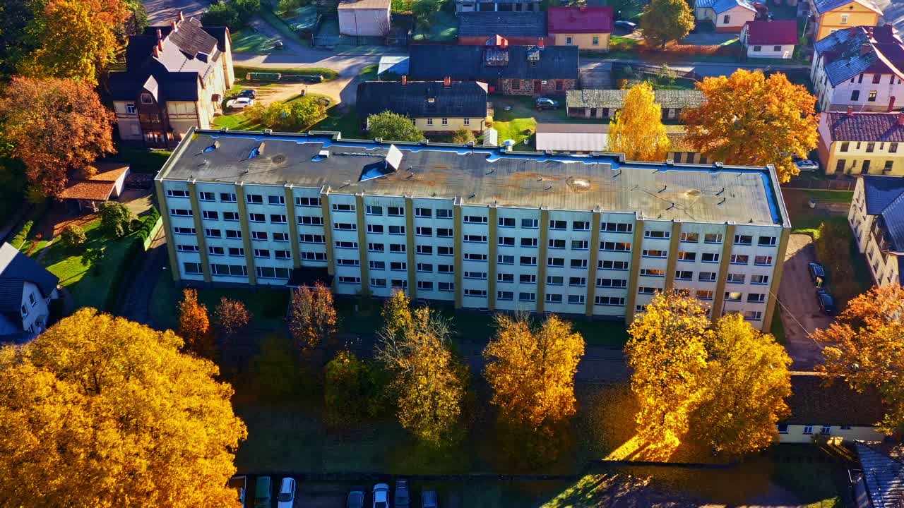 晴れた秋の日、色鮮やかな紅葉に囲まれたソビエト時代の集合住宅に住民が暮らす様子。