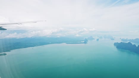 a view of the upper plane window while floating in the air, overlooking the mountains and natural water resources along the coast of thailand