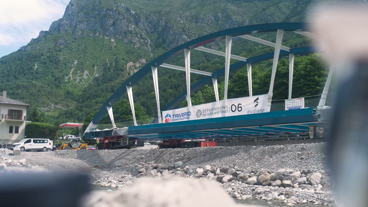 Bridge construction site in scenic Tende with heavy rigging, set against a mountain backdrop