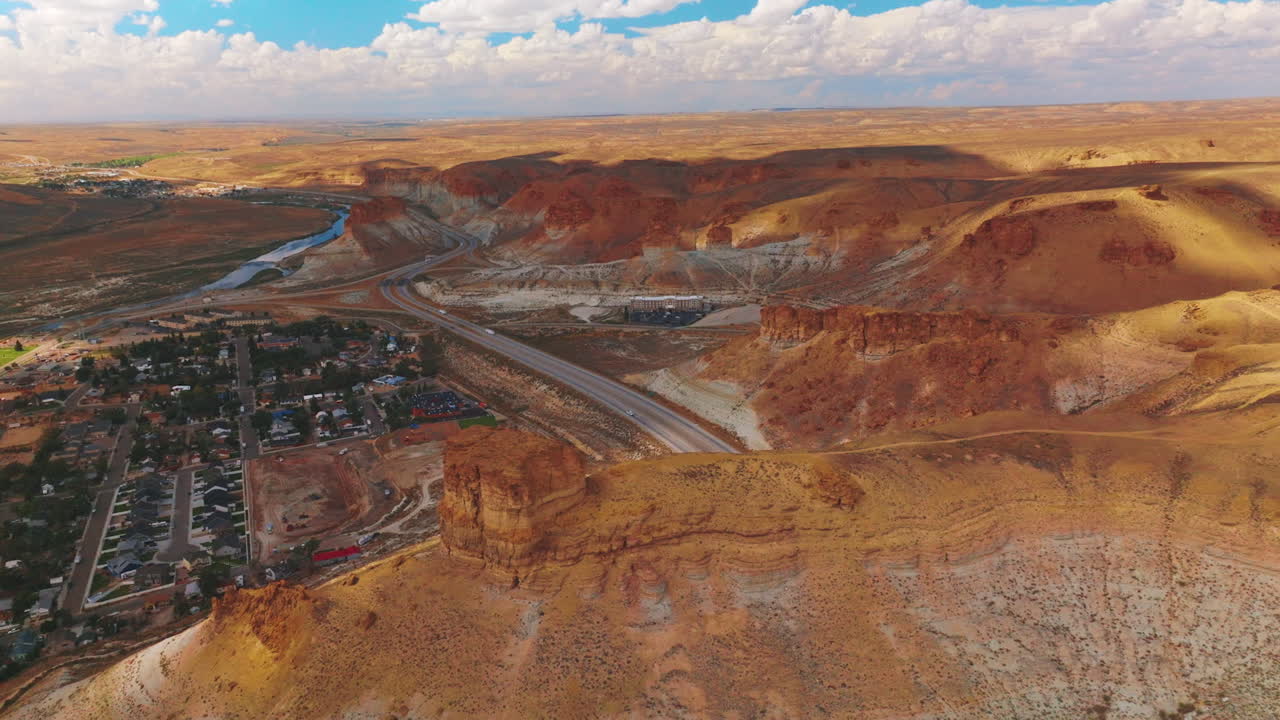 Cozy city surrounded by the bare yellow rocks. Highway through the desert in the mountains. Cloudy sky at backdrop.
