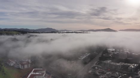 Aerial high dolly shot of distant hills peeking above the fog in Santa Rosa, California. 4K