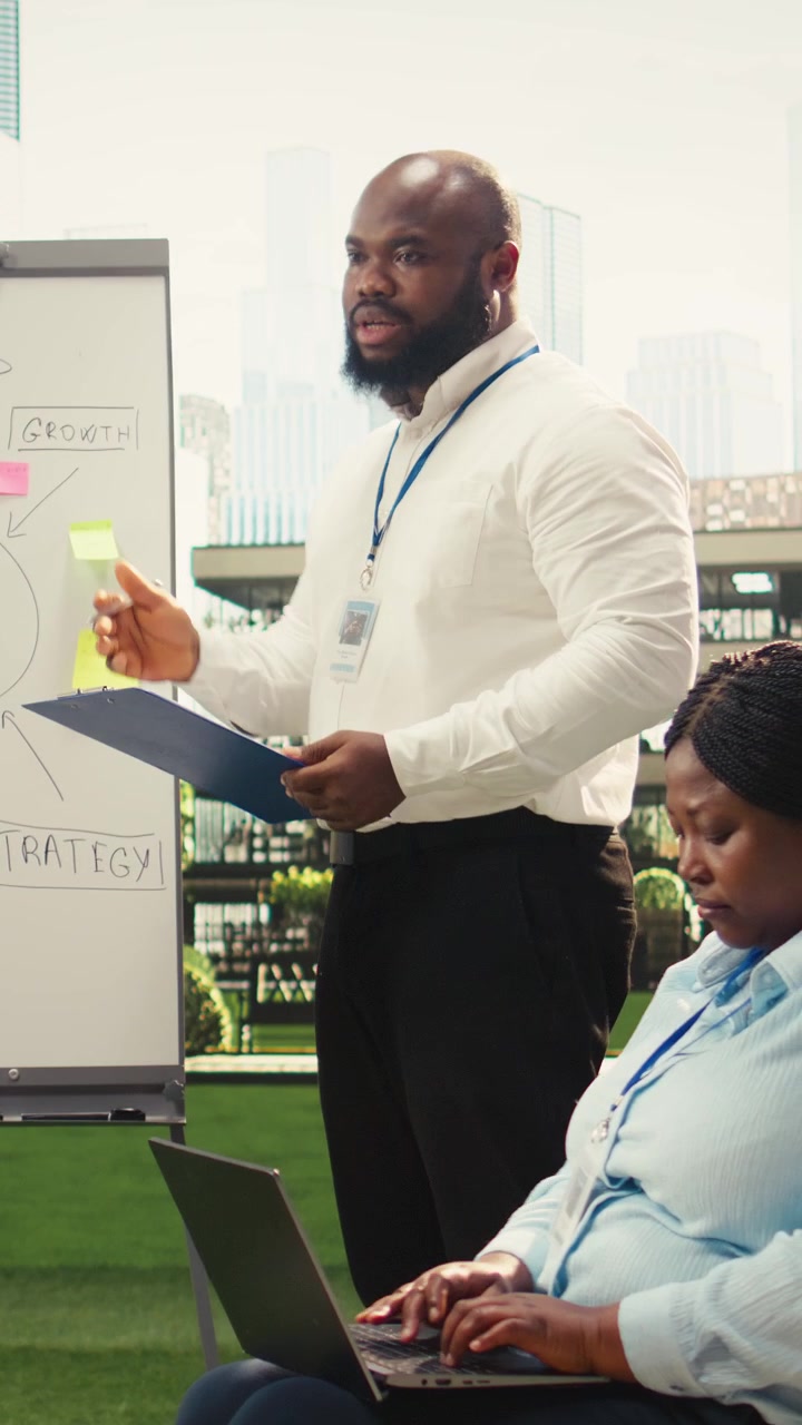 Vertical Video Diverse business presenters explaining vision board with sticky notes