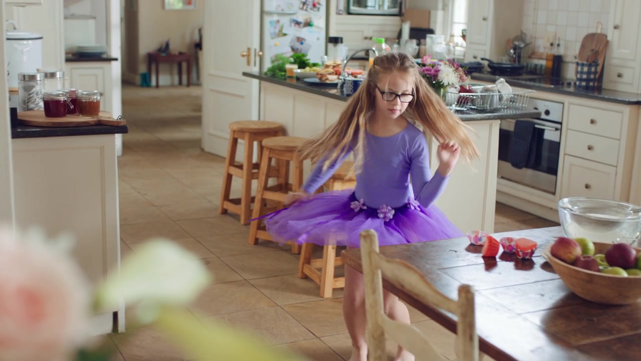 Bambina che balla con un tutù viola in cucina