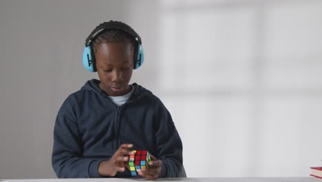 studio shot of boy on asd spectrum solving puzzle cube wearing ear defenders 1