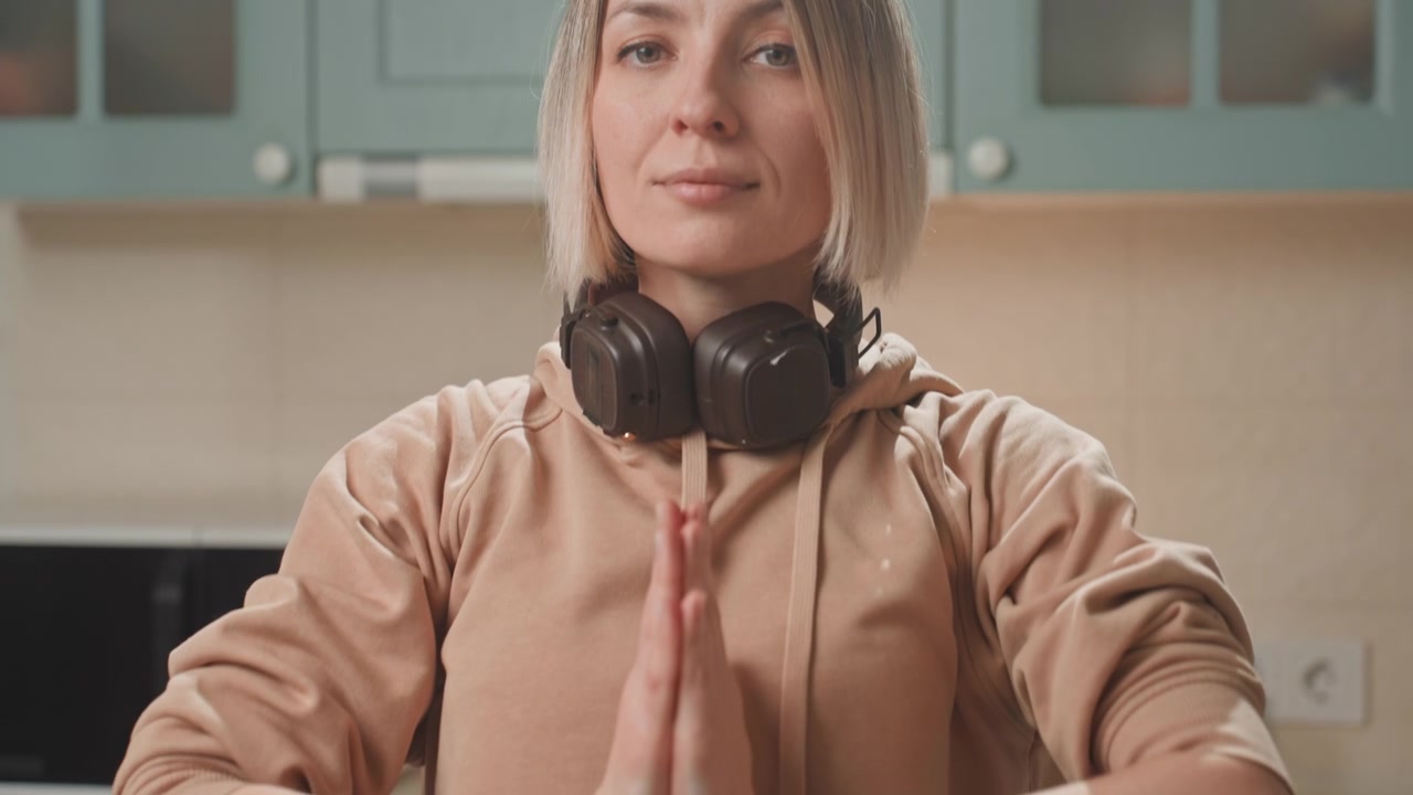 Woman pauses for mindful breathing. Caucasian woman peacefully engages in mindfulness practice indoors. Woman in peaceful setting concentrates on breathing and presence with headphones on