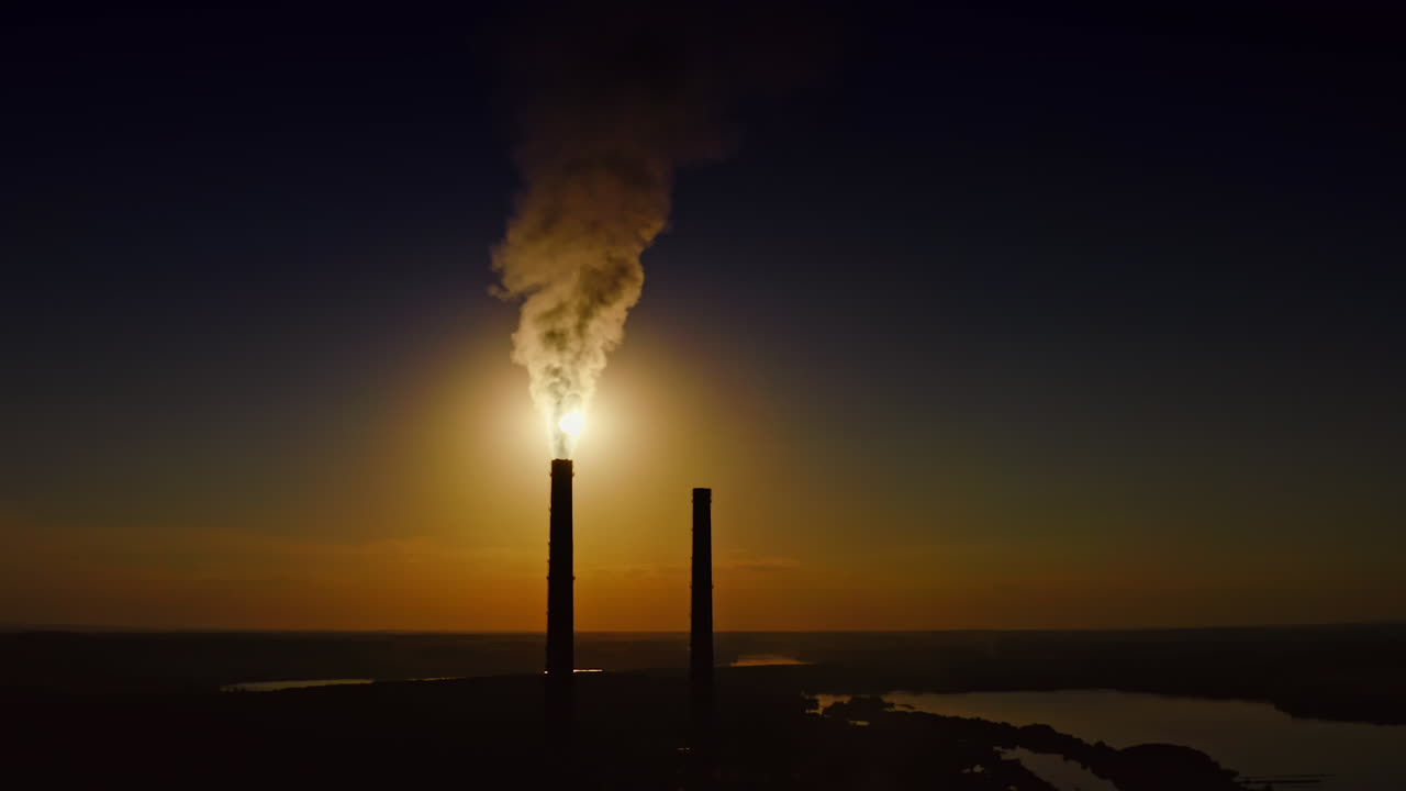 Dense smoke from pipes at sunset. Massive fumes released from industrial chimney into the environment. Nature in danger.