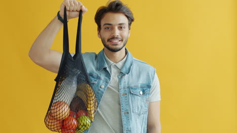 man holding a mesh bag with fruits and vegetables