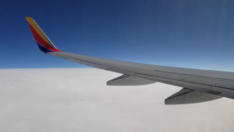 flying in an airplane and looking out the window at the airplane wing and the clouds