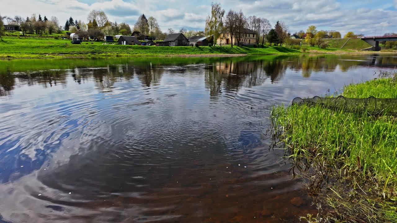 Serene River Landscape with Village and Fishing Net