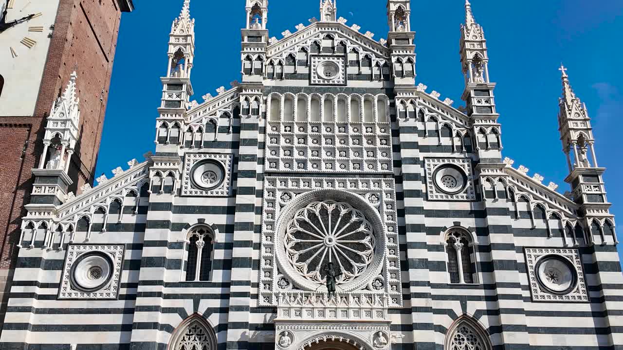 The gothic architecture of the Duomo di Monza is captured under clear daylight, emphasizing its intricate facade and Italian elegance