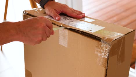 a person carefully opens a cardboard box using a knife in a well-lit indoor setting