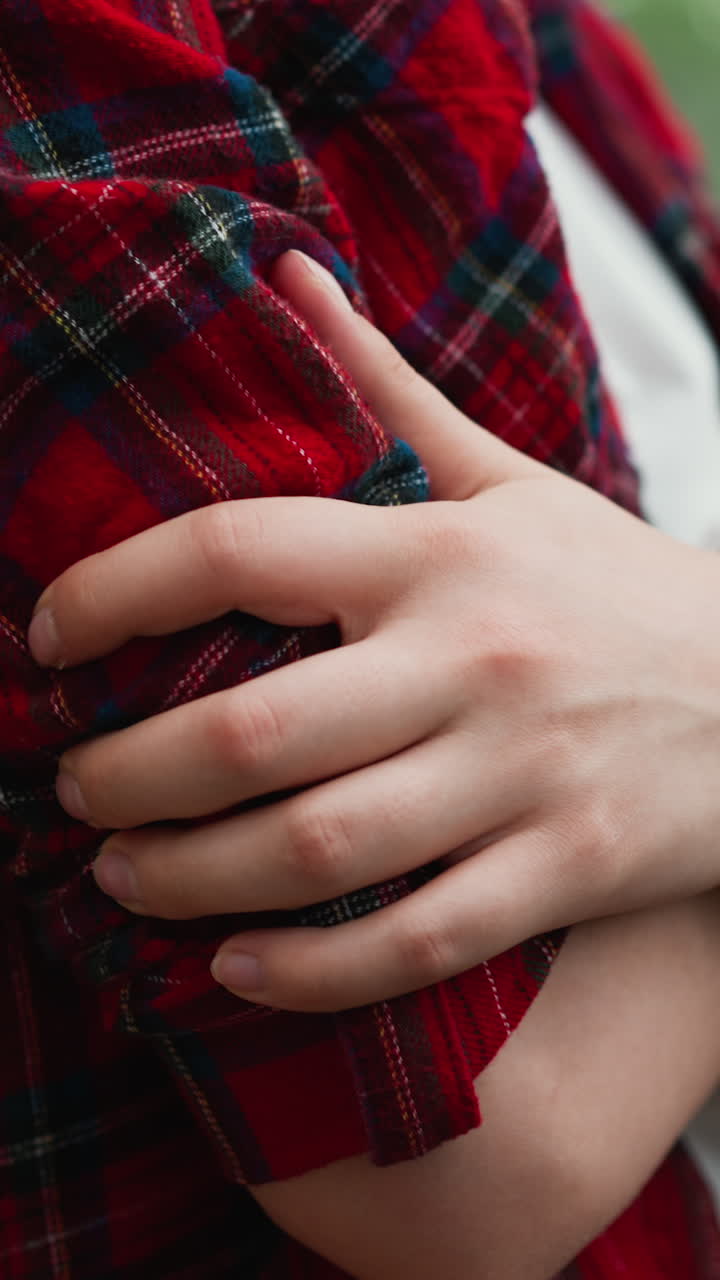 la dama encuentra consuelo en el abrazo de sí misma en casa. la mujer de camisa roja busca calor cruzando estrechamente los brazos en expresión de comodidad. profundidades de desánimo
