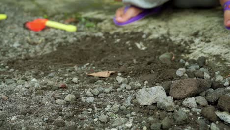 close up shot of children playing with stone sand and truck toy