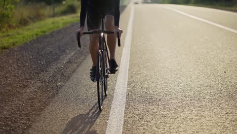 cropped front view of a male cyclist rides bicycle along and empty track