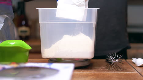 weighing flour on a chef's measuring scale to add to a homemade family recipe - slow motion isolated