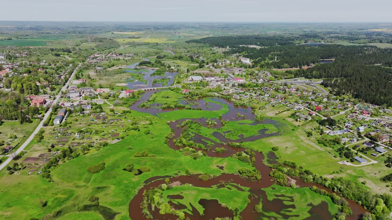 Scenic drone side flight showing flooded Abava River winding through Kandava