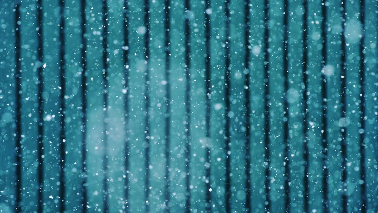 Winter scene with snowflakes falling over metallic blue surface in slow motion