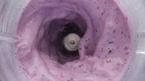 closeup berry dairy cocktail swirling inside blender in super slow motion.