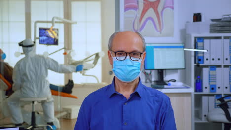 portrait of elderly man with mask in dental office looking on camera