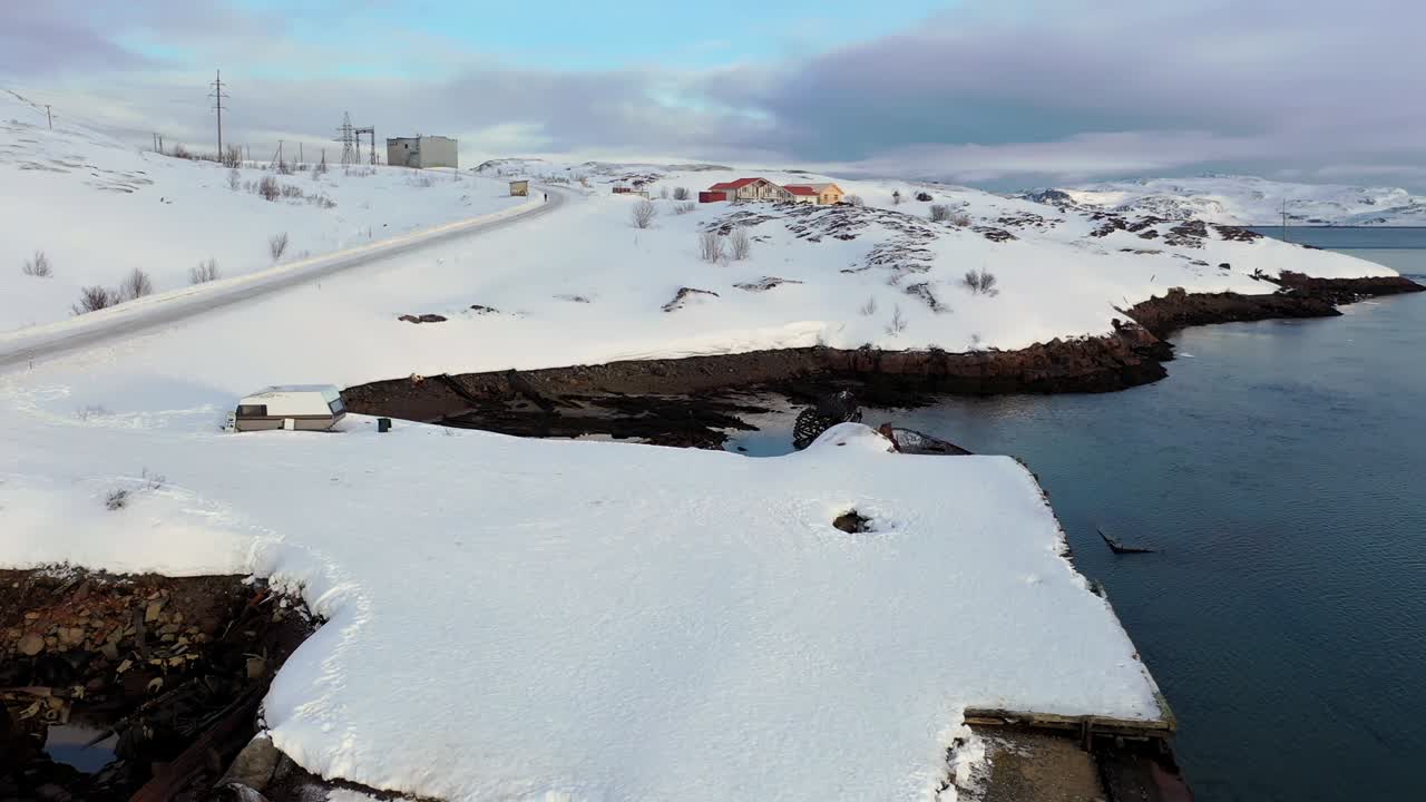 배가 침몰한 후 파괴된 배와 함께 겨울의 눈 인 바다 연안의 공중 사진. 바렌츠 해 연안의 오래된 침몰 된 어선.