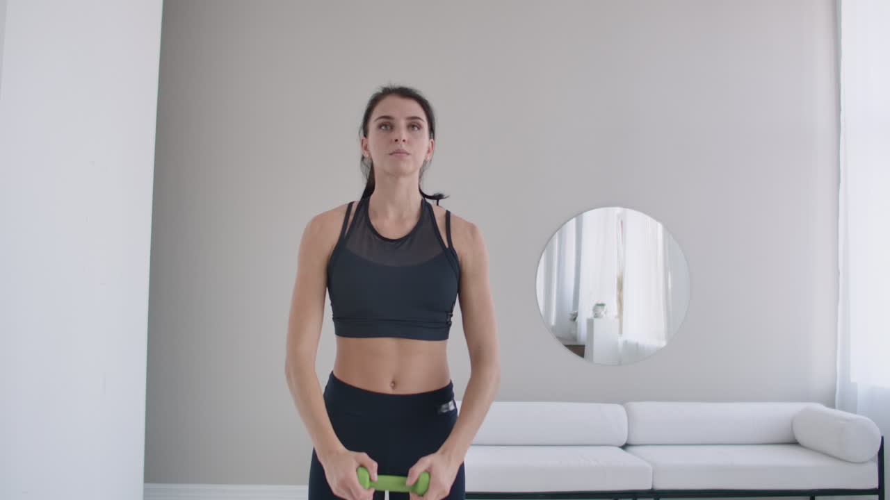 Brunette girl does warm-up and exercises in her apartment in the morning turns the body blindly and right with arms straightened.
