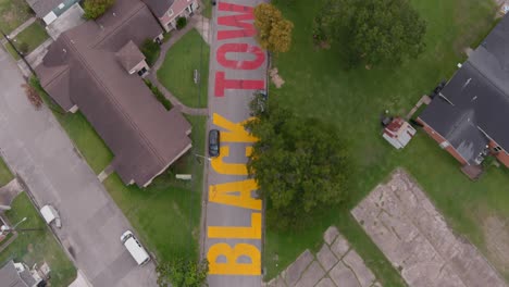 bird eye view of a large "black towns matter" sign painted on street in houston historical independence heights district