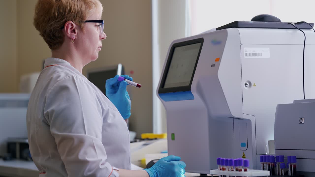 Laboratory worker in a modern microbiology cabinet. Side view of a female in medical uniform working on a special equipment for testing blood samples in research laboratory.