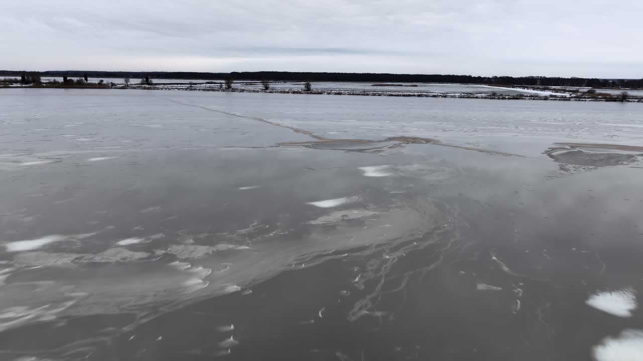 An aerial view of ice chunks and mud spots floating on the water surface in wintertime. Europe Lithuania.