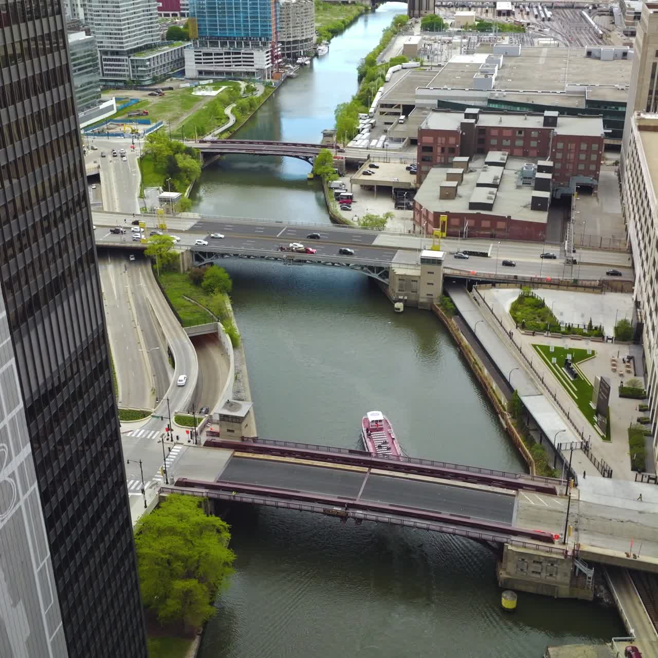 Quick cars moving by the bridges over Chicago River. Big boat sailing by the river. Aerial perspective