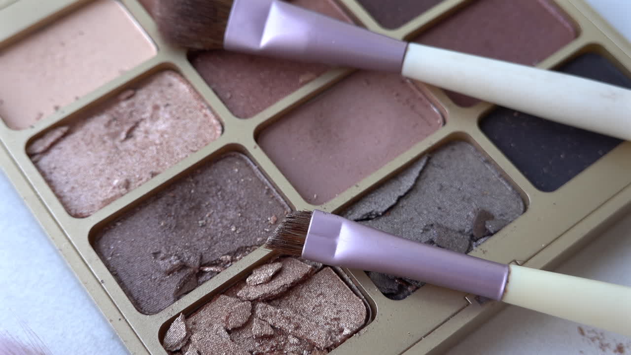 Close up of two purple make-up brushes on an eyeshadow palette