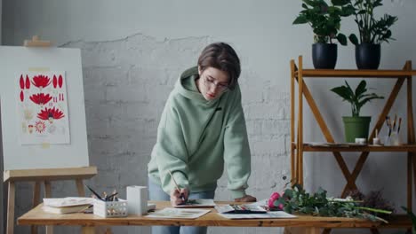 mujer pintando flores en su estudio de arte